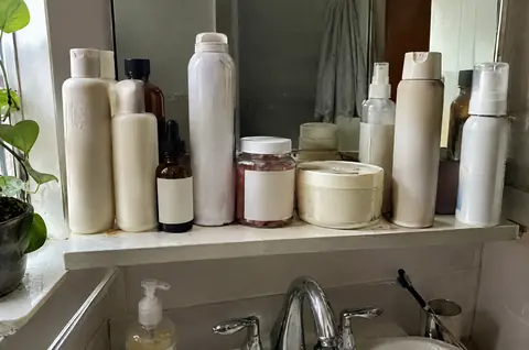 Crowded bathroom shelf full of half-used hair products
